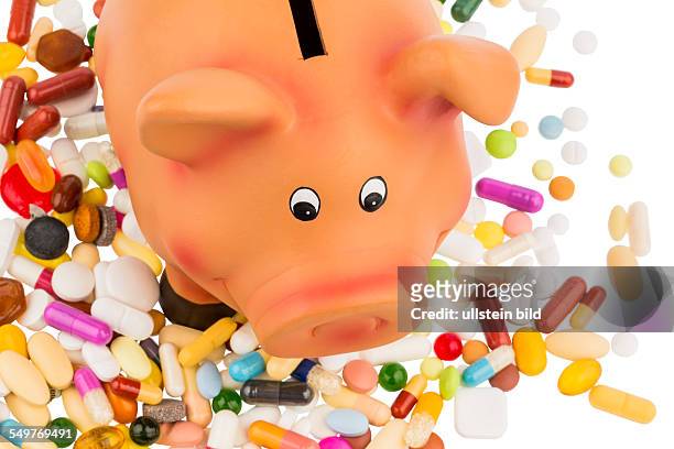 Tabletten liegen neben einem Sparschwein. Symbolfoto für Kosten in der Medizin und Pharmaindustrie