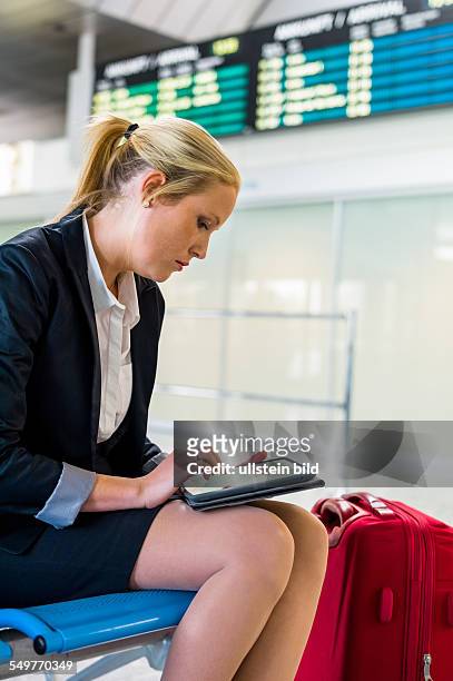 Eine Geschäftsfrau mit Koffer und Tablet Computer auf einem Flughafen. Mobilität und Kommunikation bei Geschäftsreisen. Roaming Gebühren im Ausland