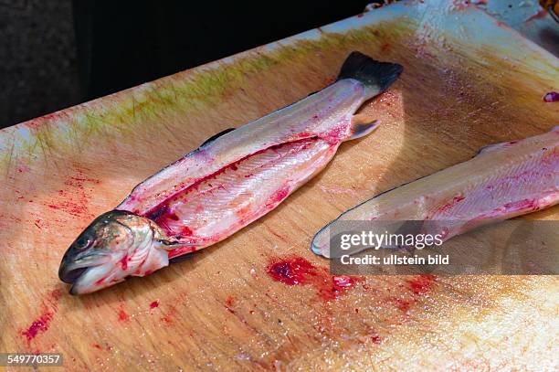 Ein Fisch auf einem Fischmarkt wird vom Fischer filetiert