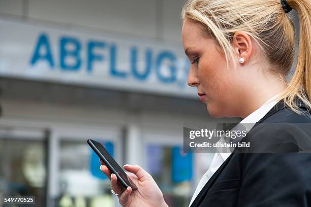 Geschäftsfrau schreibt am Flughafen SMS. Roaming Gebühren im Ausland
