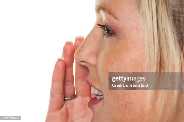 Eine junge Frau hält die Hand zum Mund und erzählt ein Geheimnis weiter.