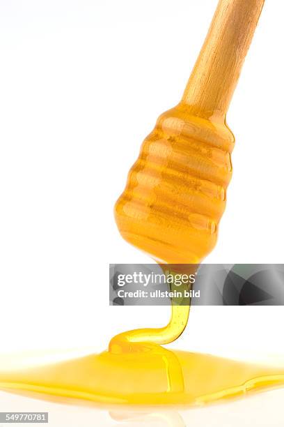 Ein Löffel wird in einen Topf mit Honig gehalten. Isoliert vor weißem Hintergrund