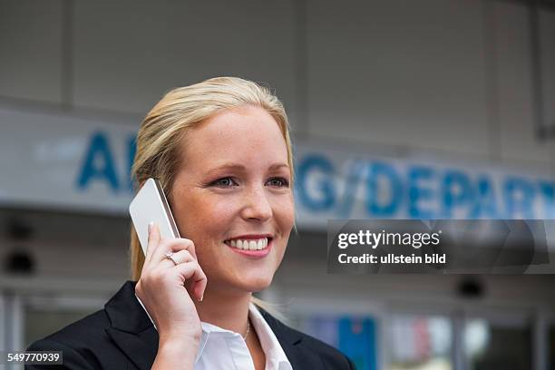 Eine Geschäftsfrau telefoniert mit ihrem Handy am Flughafen. Roaminggebühren bei Smartphones im Ausland