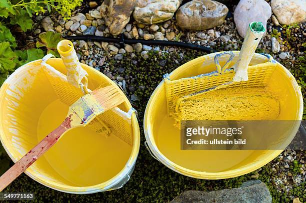 Farbkübel eines Malers. Hausfassade wird gelb gestrichen. Renovieren und sanieren