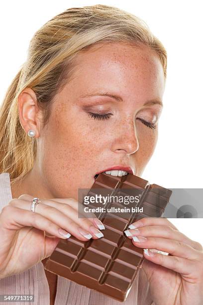 Eine junge Frau ist genussvoll eine Tafel Schokolade