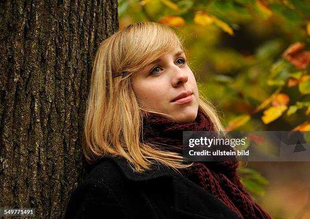 Goldener Herbst. Blonde junge Frau mit weinrotem Wollschal im Wald