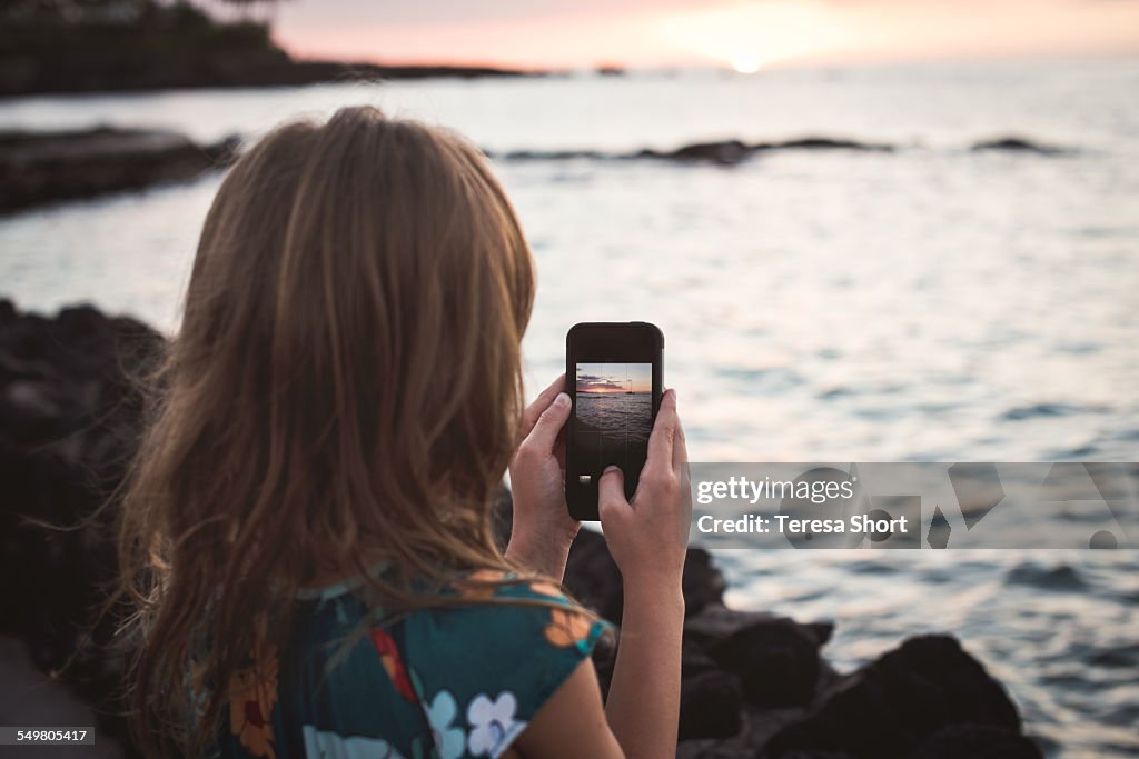 Girl Using SmartPhone to take picture of sunset