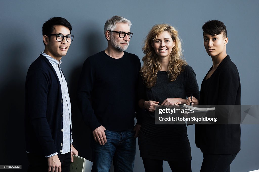 Portrait of men and women holding papers