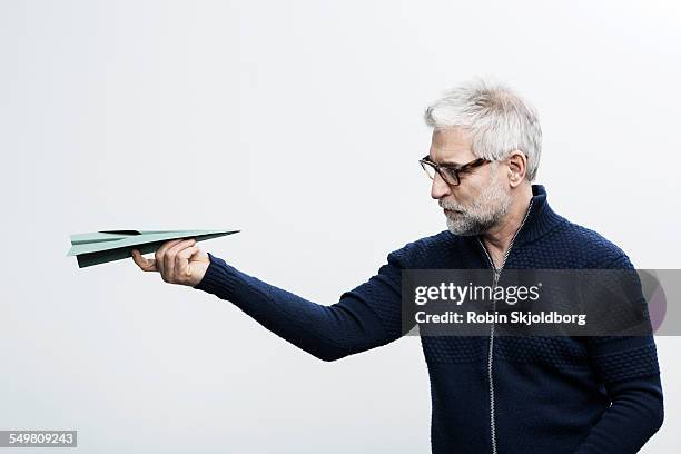 grey haired holding paper airplane - innovation white background stock pictures, royalty-free photos & images