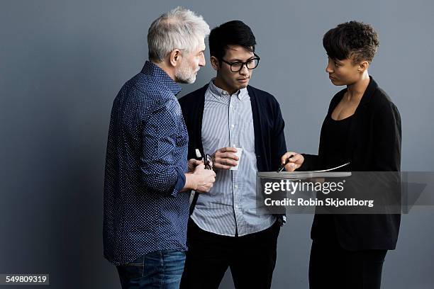 men and woman with pen and paper talking - three people standing stock pictures, royalty-free photos & images