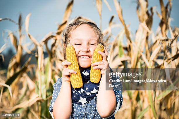 girl holding corn on the cob in field - alexandra dost stock-fotos und bilder