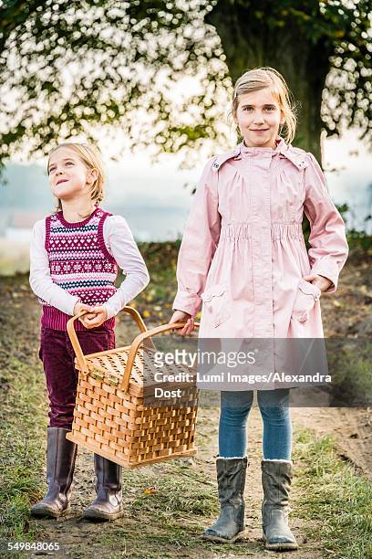 two girls carrying picnic basket - alexandra dost stock-fotos und bilder