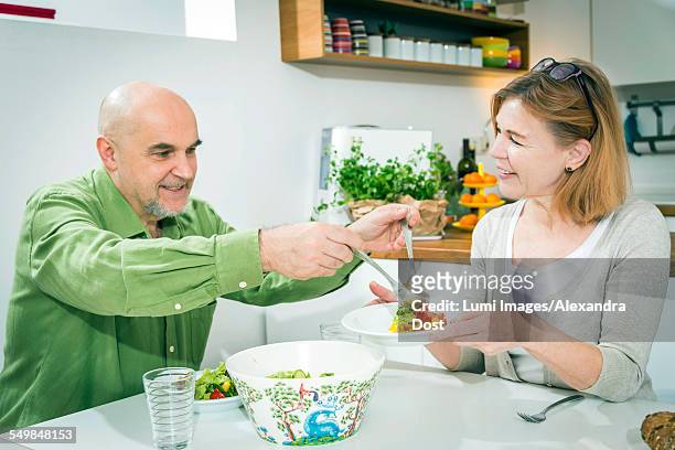 senior couple eating together in kitchen - alexandra dost stock-fotos und bilder