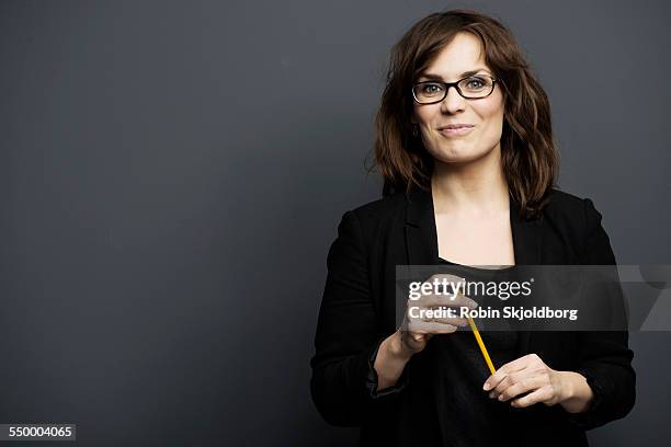 smiling woman with glasses holding pencil - pant suit stockfoto's en -beelden