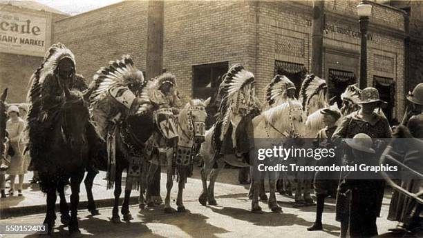 Group of Native Americans in full ceremonial dress wait on horseback to join the Frontier Days parade, Cheyenne, Wyoming, circa 1930.