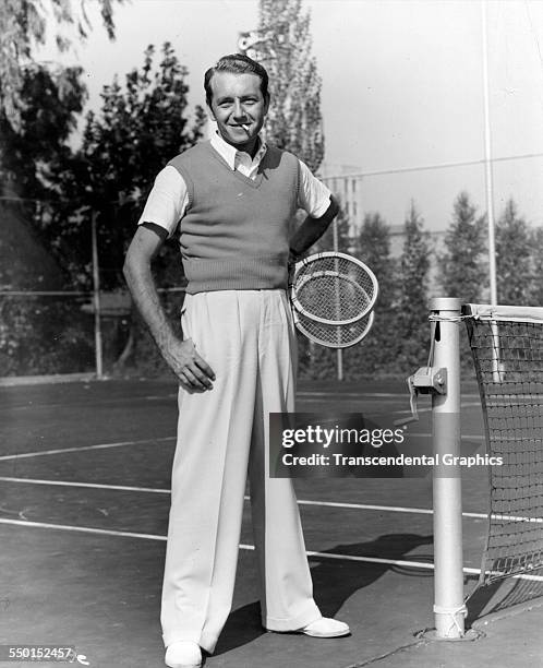 Actor Paul Henreid pauses for a photo by the tennis courts while on vacation, Florida, circa 1940.