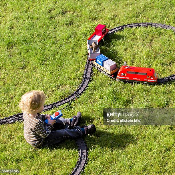 Boy, 2 years, playing with electric train set in the garden