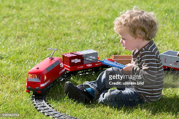 Boy, 2 years, playing with electric train set in the garden