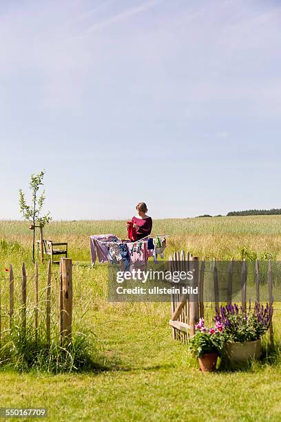 Woman, 35 years, drying the laundry in a rural garden