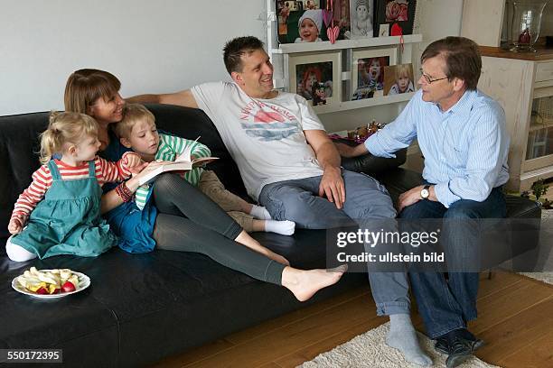 Scene family: father, mother and two children sitting on the sofa. The grandfather came to visit and talks with parents. The children read a...