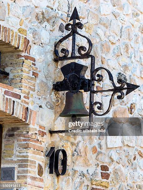 Alte Glocke an einer Hausmauer eines Steinhauses