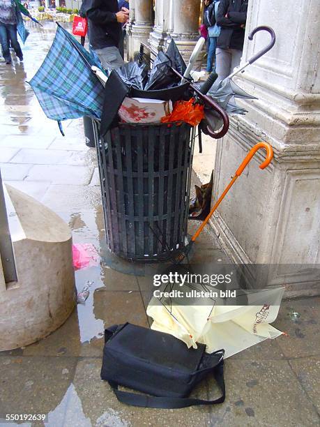 Nach längeren Regenfällen stehen weite Teile des Markusplatzes unter Wasser, Regenschirmreste werden im Papierkorb abgelagert, aufgenommen in Venedig...