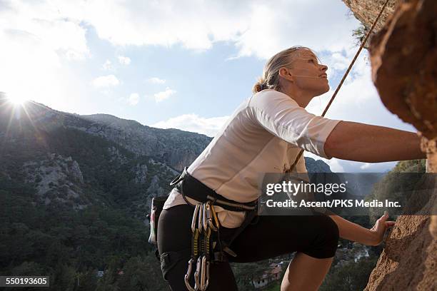 rock climber looks upwards to route above, sunrise - perseverancia fotografías e imágenes de stock