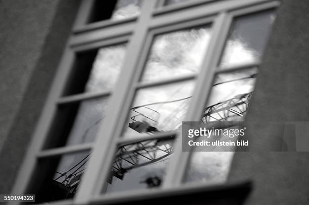 Baukran spiegelt sich in einem Fenster in der Erich-Weinert-Straße in Berlin-Prenzlauer Berg
