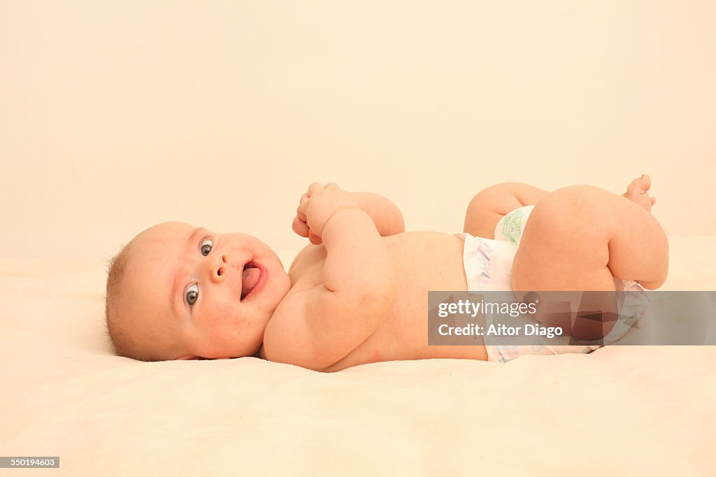 Baby boy on a bed and smiling. 3-4 months old.