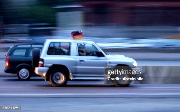 Auto rast mit Deutschlandflagge durch das abendliche Berlin News