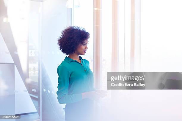businesswoman looking out of window in thought - escritório tecnologia olhar em frente imagens e fotografias de stock
