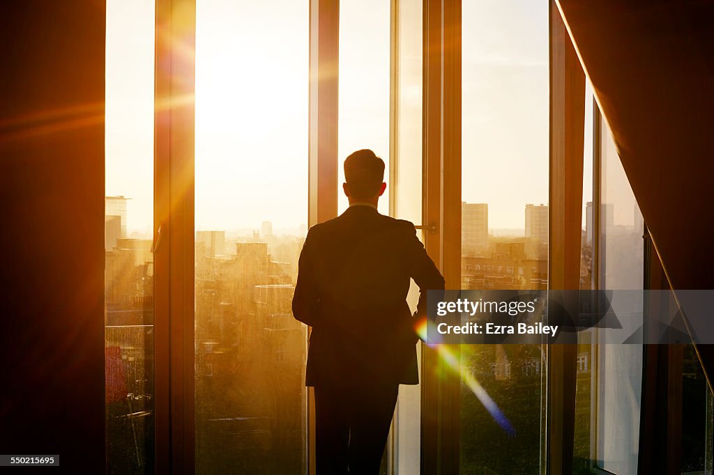 Businessman looking out over city at sunrise