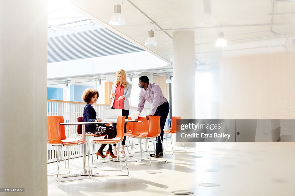 Three business people chatting over laptop