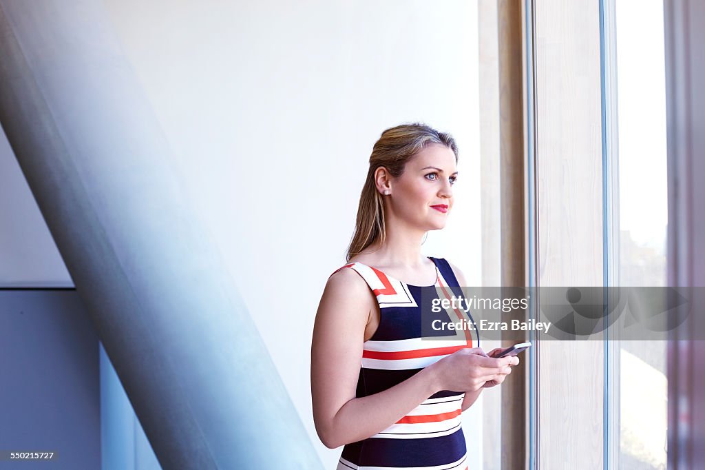 Business woman using phone looking out of window