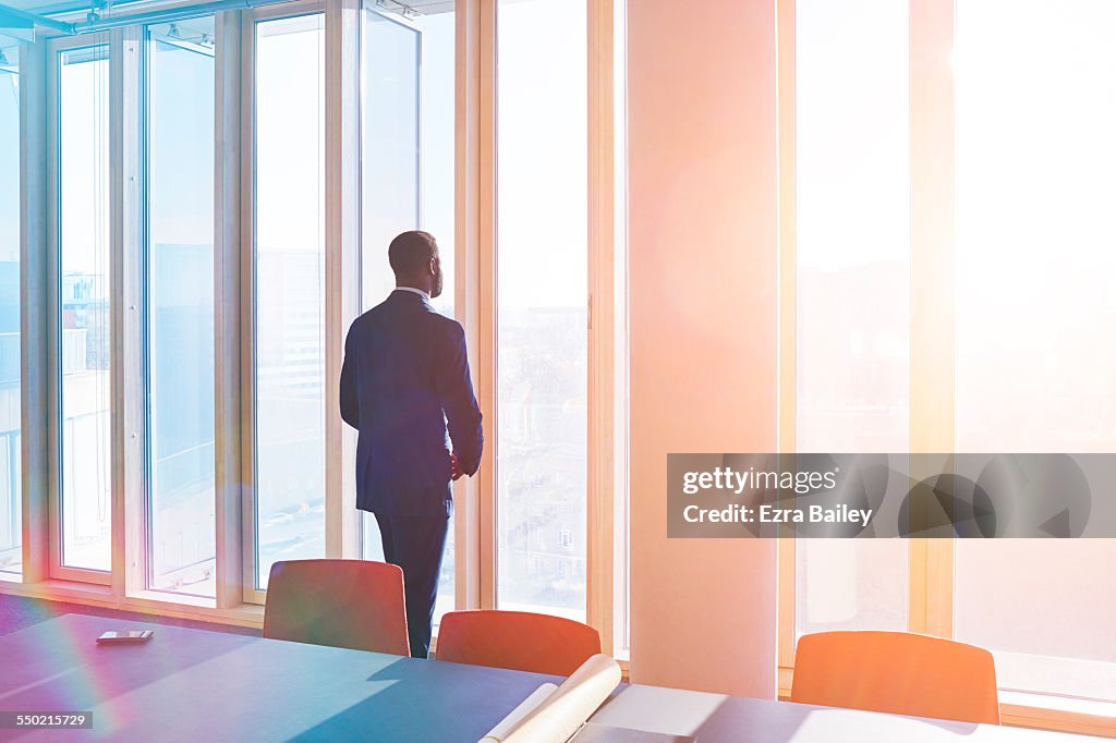 Businessman looks out of office window over city