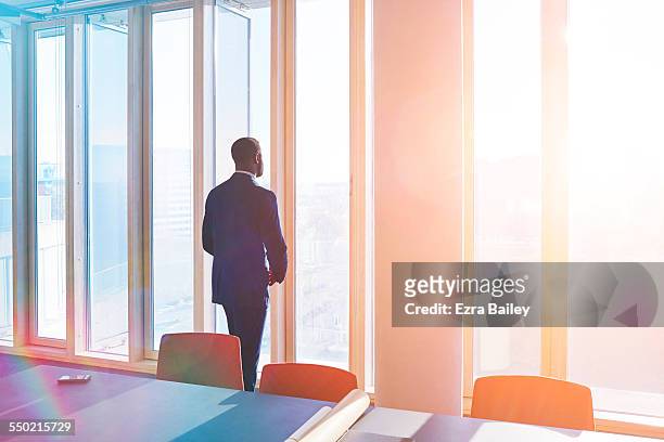 businessman looks out of office window over city - opportunity stock pictures, royalty-free photos & images