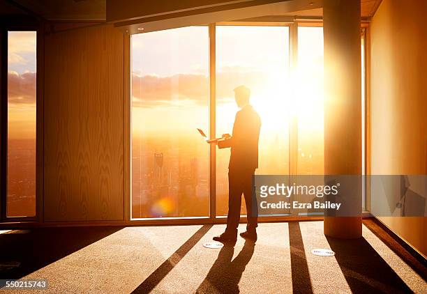 businessman looking out over the city at sunrise. - background light stock pictures, royalty-free photos & images