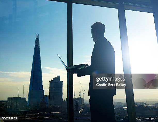 businessman looking over city holding laptop - future cityscape stock pictures, royalty-free photos & images