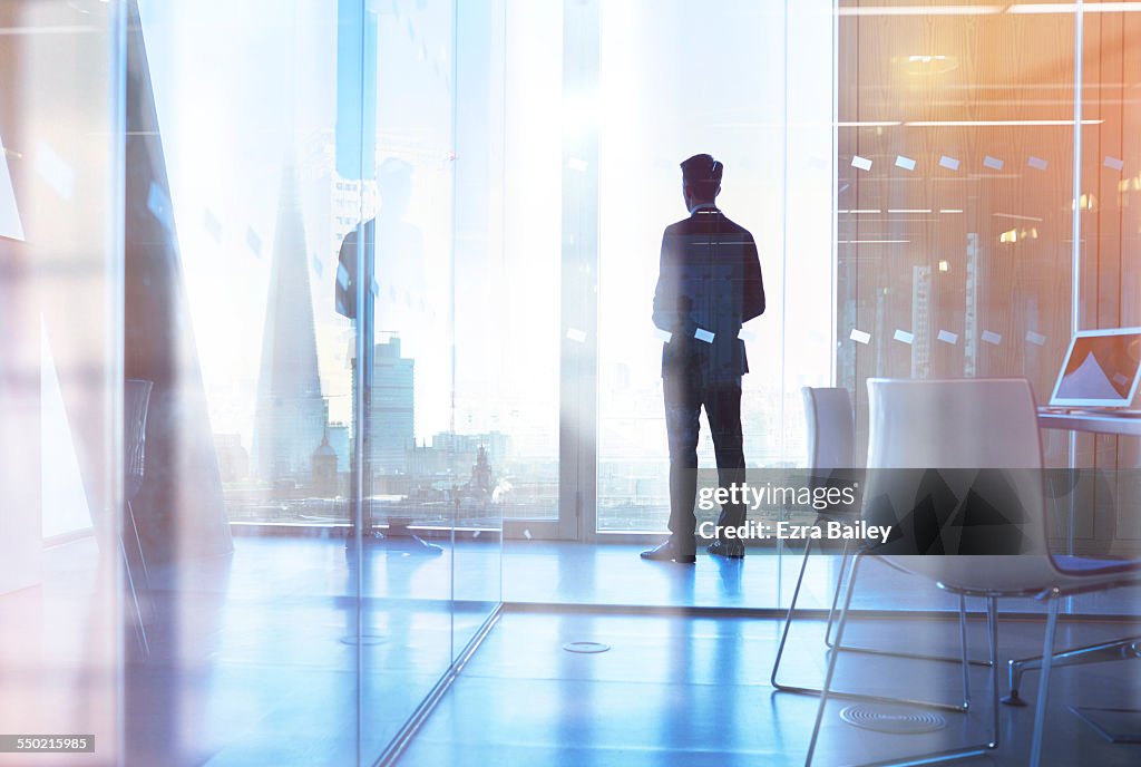 Businessman looking out of office over city