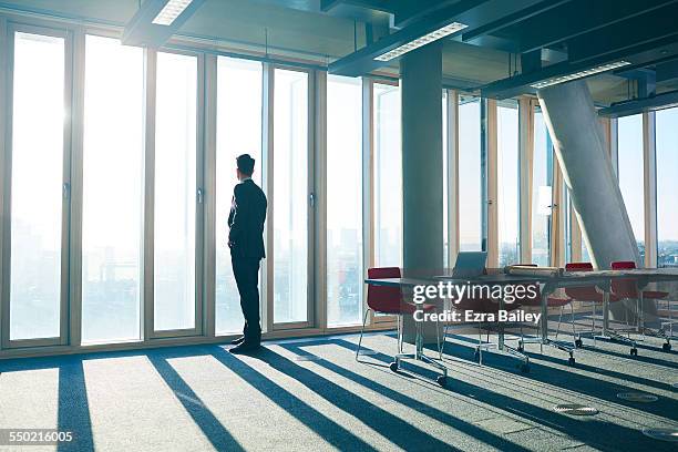 businessman looking out of office over city - men suit light stock pictures, royalty-free photos & images