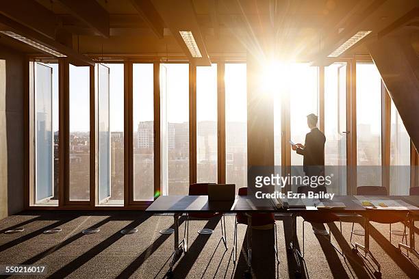 businessman on tablet looks out across city - back of office chair stock pictures, royalty-free photos & images