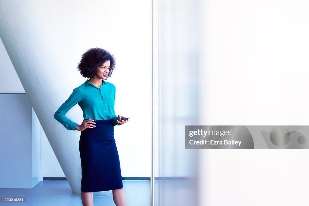 Business woman using phone looking out of window