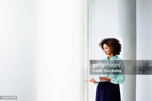 businesswoman with laptop looking out of window. - red blouse fotografías e imágenes de stock