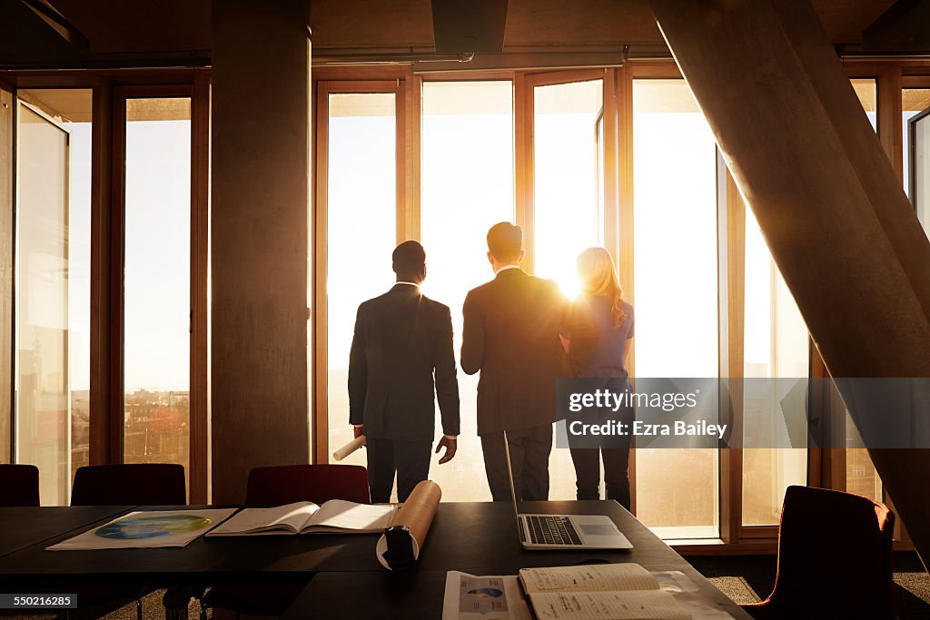 Colleagues looking out across city at sunrise