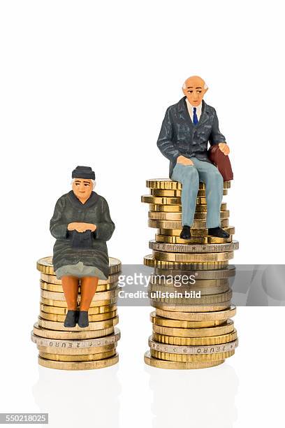Rentner und Pensionistin auf unterschiedlich hohen Geldstapeln. Symbolfoto für Einkommensunterschiede.