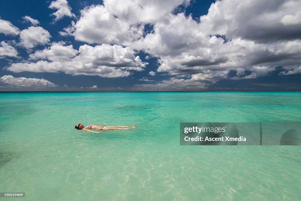 Woman floats in calm sea shallows, tropics