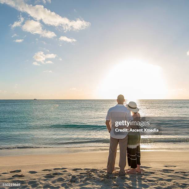 couple relax on beach, watch sunrise over sea - barbados beach stock pictures, royalty-free photos & images