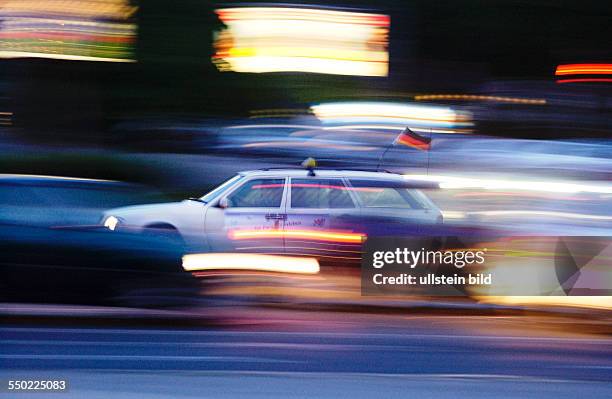 Taxi rast mit Deutschlandflagge durch das abendliche Berlin