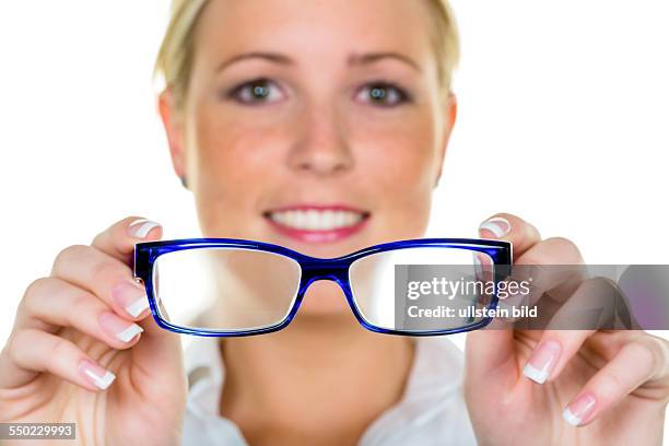 Eine Frau hält eine Brille in der Hand. Symbolfoto für schlechtes Sehen und Fehlsichtigkeit