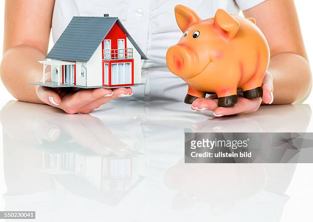 Eine Frau mit einem Haus und einem Sparschwein. Die richtige Finanzierung für den Hauskauf.